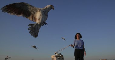 Loubna Hamdan stands on her loft's rooftop, where she leaves food out for pigeons, as she swings an empty slingshot to encourage them to fly and get exercise in Chiyah, the southern suburbs of Beirut, Lebanon, July 10, 2025. (AP Photo)