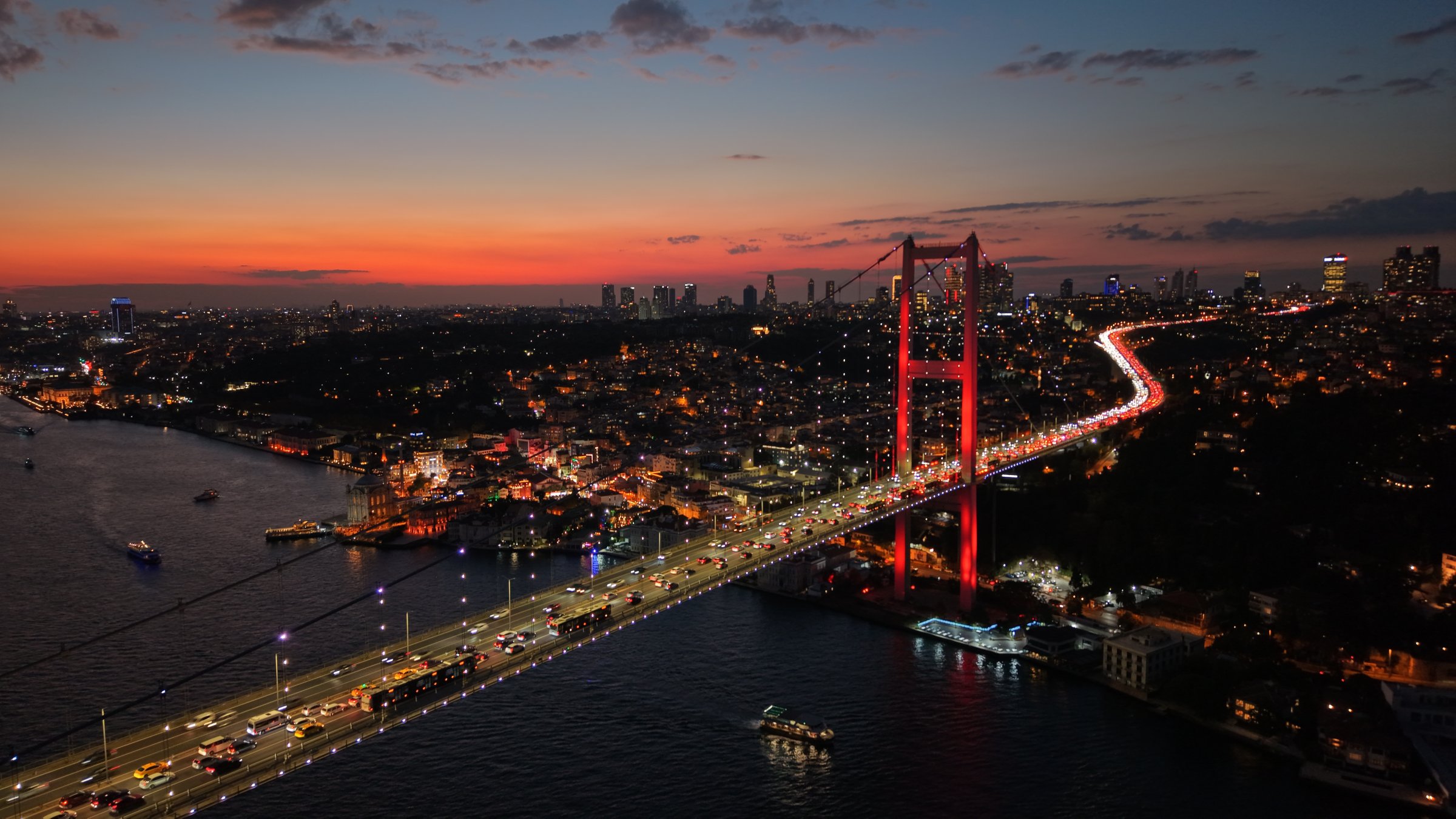 The Bosporus Bridge glows red at night as traffic flows beneath Istanbul’s skyline, Istanbul, Türkiye, Oct. 1, 2025. (Shutterstock Photo)