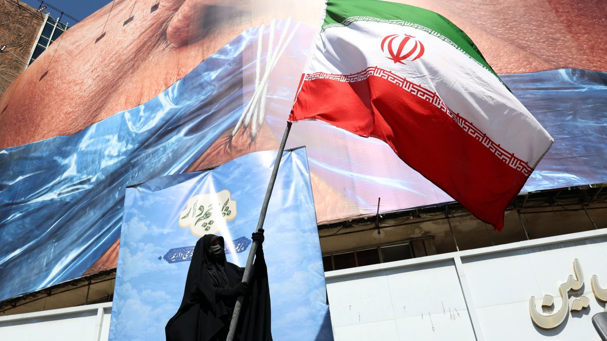A woman holds Iran’s national flag in front of a huge anti-U.S. billboard referring to U.S. President Donald Trump and the Strait of Hormuz at Valiasr Square in Tehran, Iran, May 11, 2026. (EPA Photo)